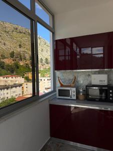 a kitchen with a counter with a microwave and a window at Sea You Soon Apartment in Shëngjin