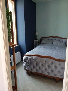 a bedroom with a bed with blue walls and a window at Maison de campagne in Maussac