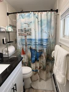 a bathroom with a shower curtain with a seascape at Salty & Sweet 303 in Old Orchard Beach +33 photos