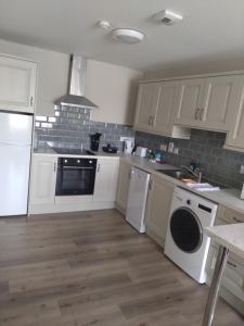 a kitchen with white cabinets and a washer and dryer at Codladh Samh Apartment No 2 in Templemore