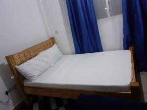 a small bed in a room with a blue curtain at Asante Studio in Mtwapa +4 photos