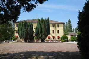 a large building with trees in front of it at Hotel Antico Casale in Vigarano Mainarda