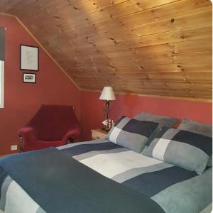 a bedroom with a bed and a red chair at Rolig sted ved havet in Sirevåg