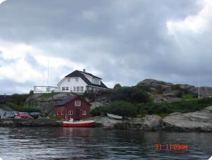 a house on a hill next to a body of water at Rolig sted ved havet in Sirevåg