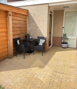 a patio with a table and chairs on a patio at Bed & Beach Zeekraal in De Koog