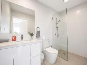 a white bathroom with a toilet and a shower at 21 Pimpama Home in Pimpama +11 photos