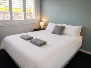 a bedroom with a white bed with two pillows on it at 21 Pimpama Home in Pimpama