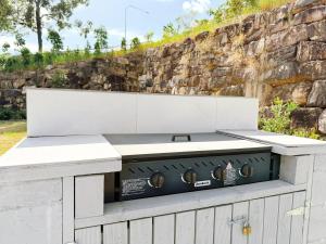 a white barbecue grill with a stone wall at 21 Pimpama Home in Pimpama
