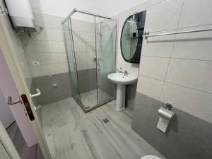 a bathroom with a glass shower and a sink at Golem Apartments in Golem