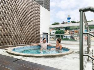 a man and woman sitting in a hot tub on a building at Puerto Santa Ana, river view 102 in Guayaquil