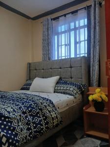 a bed with blue and white pillows and a window at Joyland B&B in Mbita