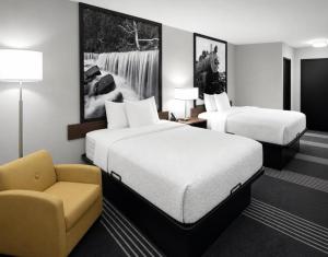a hotel room with two beds and a chair at Super 8 by Wyndham Salina I-70 in Salina +30 photos