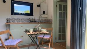 a kitchen with a table and chairs and a television at Apple Orchard Shepherd Huts in Staple Cross +28 photos