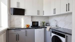 a kitchen with white cabinets and a washer and dryer at Status center in Bălţi