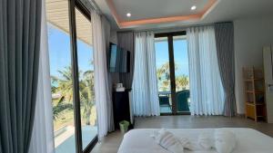 a bedroom with a bed and a large window at Sunrio Beach Hotel Sichon in Ban Plai Thon