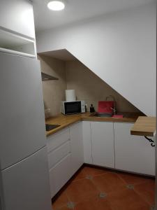 a kitchen with white cabinets and a microwave at Casa La Piedra in Constantina