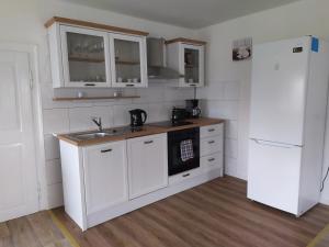 a kitchen with white cabinets and a sink and a refrigerator at Ferienwohnung Schwerg in Hohnstein +9 photos