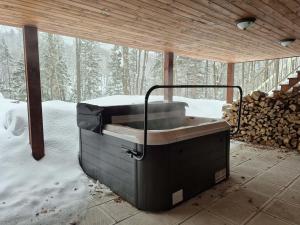 a hot tub in a room with snow on the ground at Le Cormoran in Sainte Brigitte de Laval