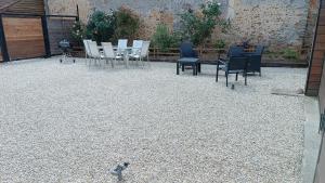 a bird walking on a gravel patio with chairs and tables at Douce Campagne in Clermont-Créans +3 photos