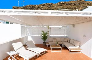 a patio with a couch and chairs and a table at Deluxe Mogán Beach Apt 2 in Puerto de Mogán