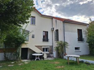 a white house with a picnic table in the yard at Ô Cottage La Barre Ormesson - 20 min Paris in Deuil-la-Barre