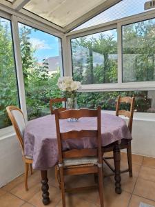 a table and chairs in a room with windows at Ô Cottage La Barre Ormesson - 20 min Paris in Deuil-la-Barre