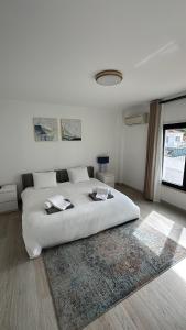 a white bedroom with a large bed and a rug at Kauai Guest House in Parede