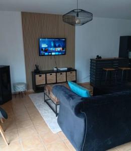a living room with a blue couch and a tv at Maison de campagne in Capelle-Fermont