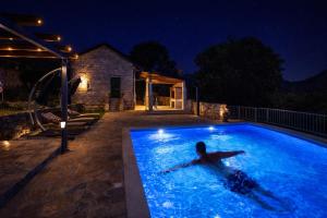 a man laying in a swimming pool at night at Villa Rosa in Ravno