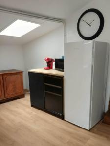 a kitchen with a refrigerator and a clock on the wall at Ma Bulle Confort in Pouzauges