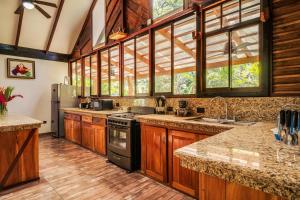 a large kitchen with wooden cabinets and a large window at Casa Shaquir H -Luxury Villa with Private Pool & Stunning Views in Puerto Viejo