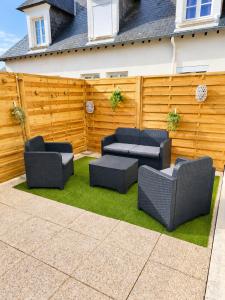 a patio with two couches and a fence at Cocon avec terrasse proche plages et centre in Dives-sur-Mer