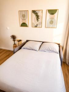 a bed in a bedroom with three pictures on the wall at Cocon avec terrasse proche plages et centre in Dives-sur-Mer