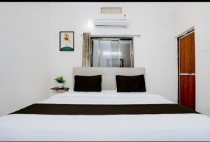 a bedroom with a large white bed with black pillows at Ayushmaan Hotel - near Jabalpur Railway Station in Jabalpur +12 photos