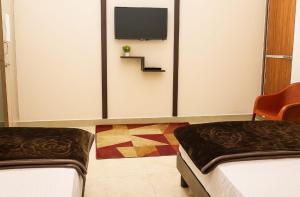 a room with two beds and a tv on a wall at Ayushmaan Hotel - near Jabalpur Railway Station in Jabalpur