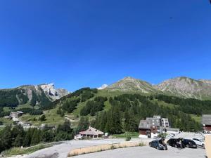 a group of cars parked in a parking lot with mountains at FOUX D ALLOS Piscine 4 personnes in Allos