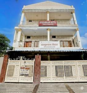 a tall white building with a sign on it at Ayushmaan Hotel - near Jabalpur Railway Station in Jabalpur