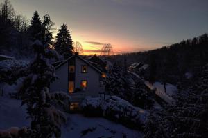 a house in the snow with the sunset in the background at Blackhillhouse - Moderne Auszeit im Harz in Osterode