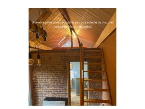 a room with a staircase and a brick wall at Le Cartot in Saint-Sauveur-dʼÉmalleville