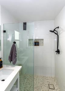 a bathroom with a glass shower with a sink at Steps to the pier! in San Clemente