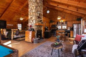 a living room with a stone fireplace in a log cabin at Cozy Cabin Retreat Near Helen Hot Tub Fireplace in Sautee Nacoochee +37 photos