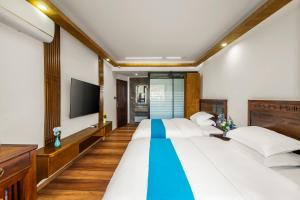 a bedroom with two beds and a flat screen tv at LQJ Riverside Guest House in Fenghuang County