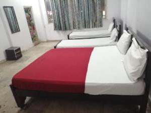 two beds in a hotel room with a red blanket at HOTEL BPR RESIDENCy in Hyderabad
