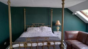 ein Schlafzimmer mit Himmelbett und Sofa in der Unterkunft Bear House B&B, Ensuite room above the Brachio Cafe, Colyton in Colyton