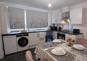 a kitchen with a table with plates and glasses on it at Fully Equipped Homely Heaven in Houghton le Spring