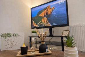 a flat screen tv on a stand with a table with a candle at Fully Equipped Homely Heaven in Houghton le Spring