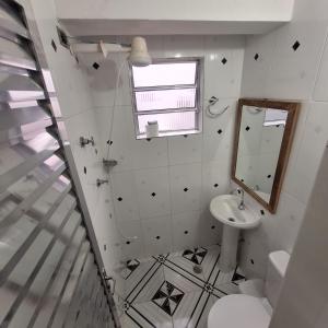 a white bathroom with a sink and a mirror at Hospedagem Henri Dunant in São Paulo