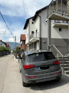 a car parked on a street next to a house at Apartman HODŽIĆ in Sarajevo