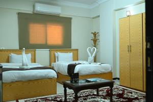 a bedroom with two beds and a table at فندق شهرزاد - Shahrazad Hotel in Banī ‘Aţīyah