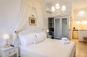 a bedroom with a large white bed with a chandelier at Villa Rose in Fira